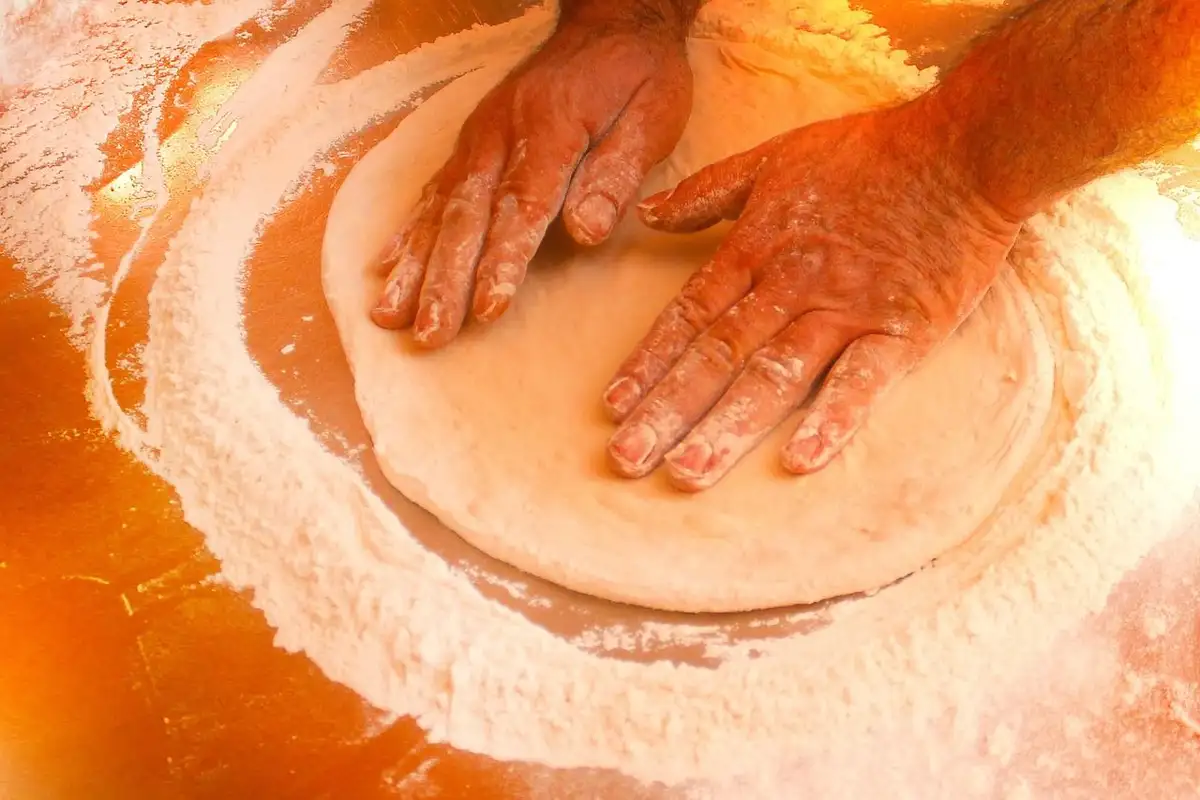 Mains de pizzaiolo qui étalent un pâton