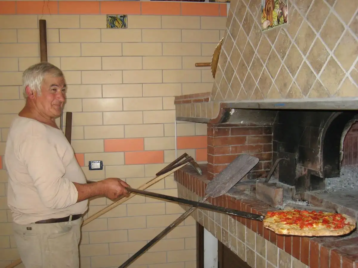 Pizzaiolo qui enfourne une pizza avec sa pelle