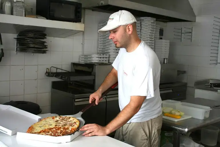 Pizzaiolo qui met une pizza en boîte pour une commande à emporter